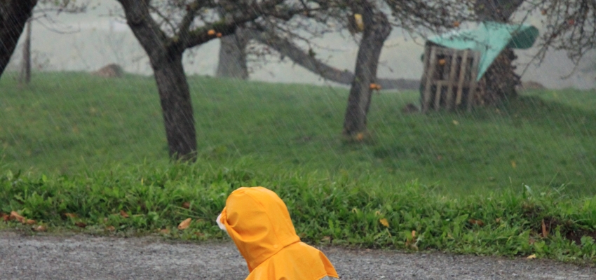 Foto: ein Kind in Gummistiefeln läuft durch eine Pfütze